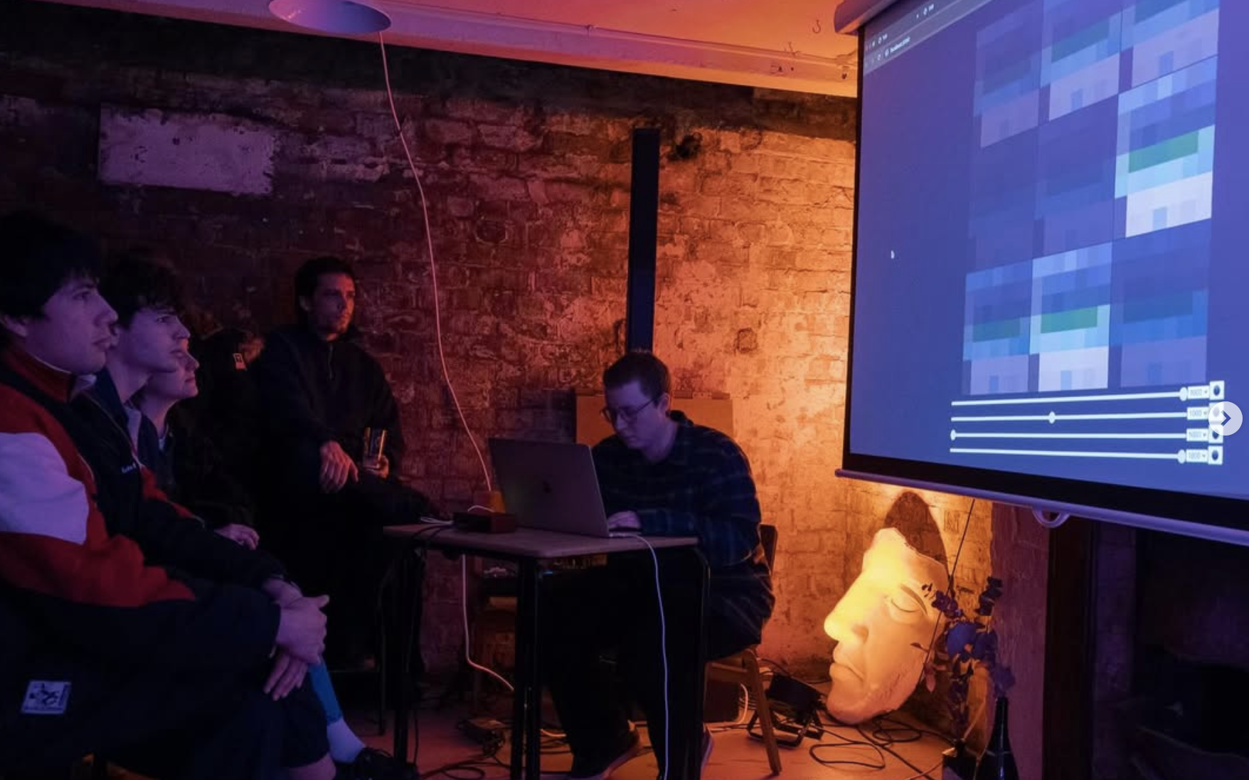 Performing in a basement space in front of a projector screen.